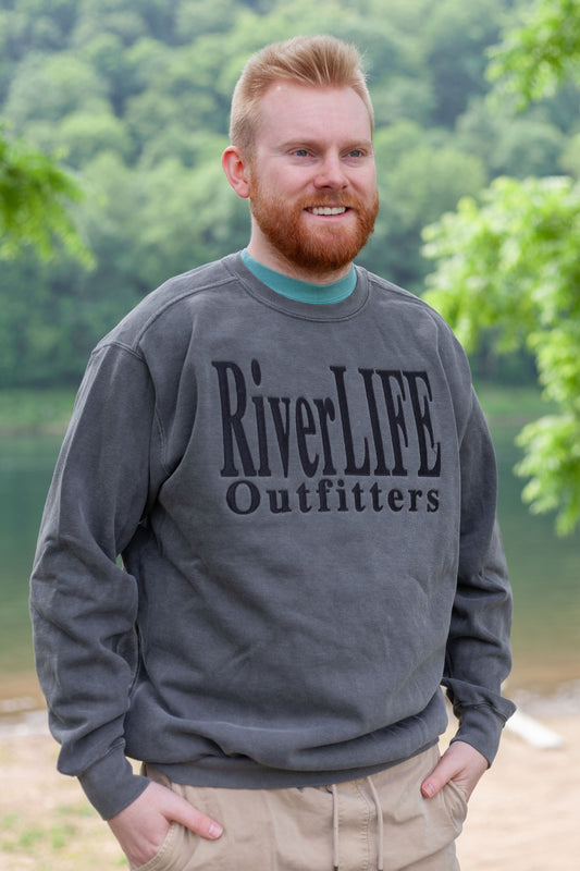 Grey crew neck sweatshirt by Comfort Colors with the words RiverLIFE Outfitters embroidered in black thread